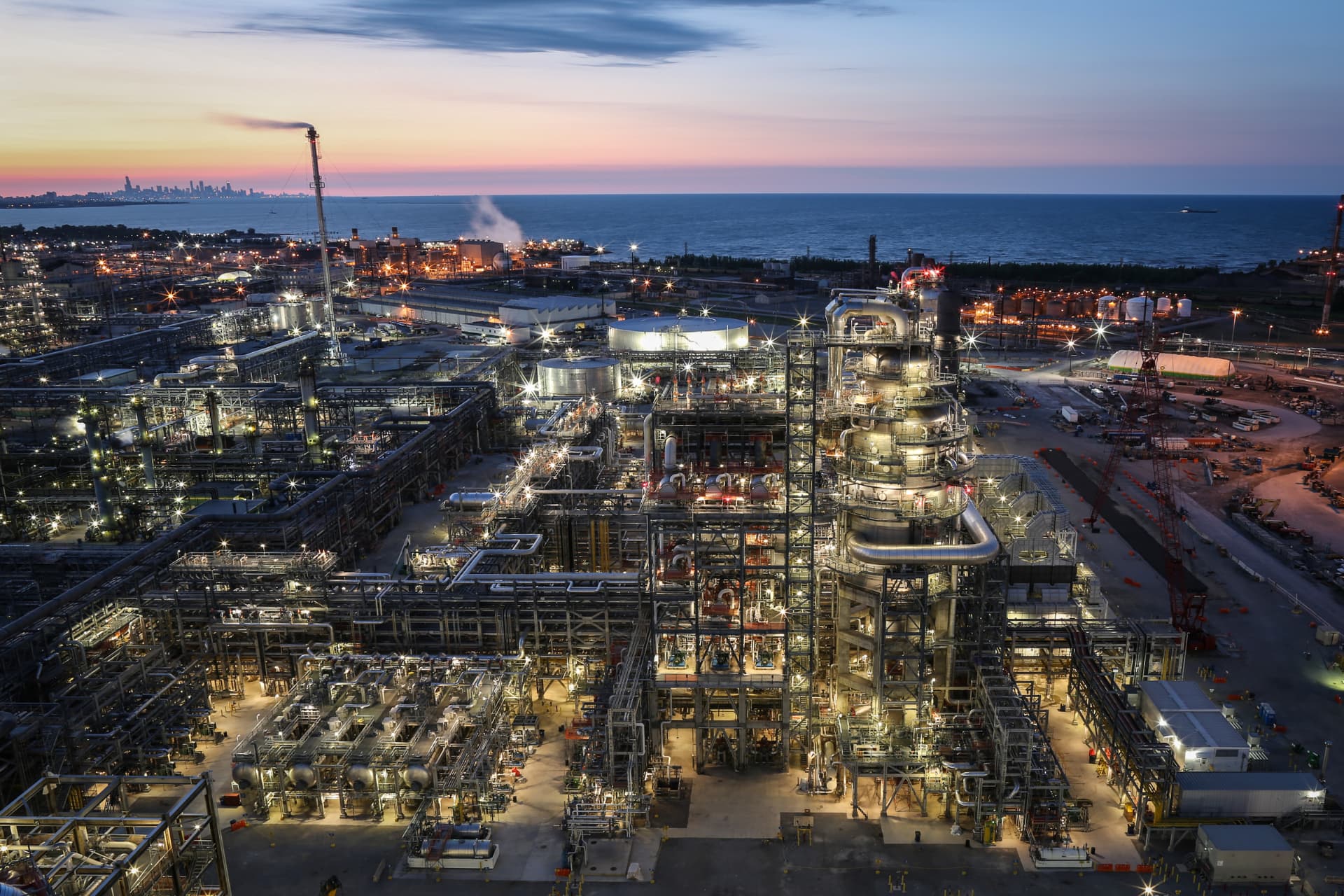 Aerial view of a Gulf Coast petrochemical refinery at dusk with illuminated process units and distillation columns