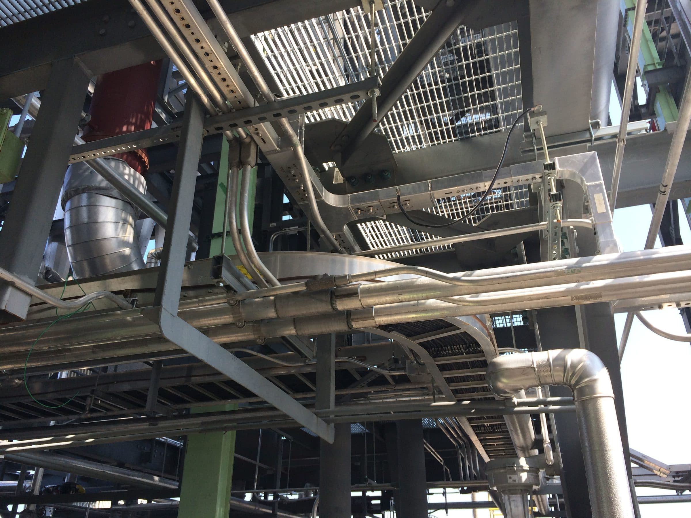 Dense instrument corridor with tubing runs, cable trays, and structural steel in a process plant